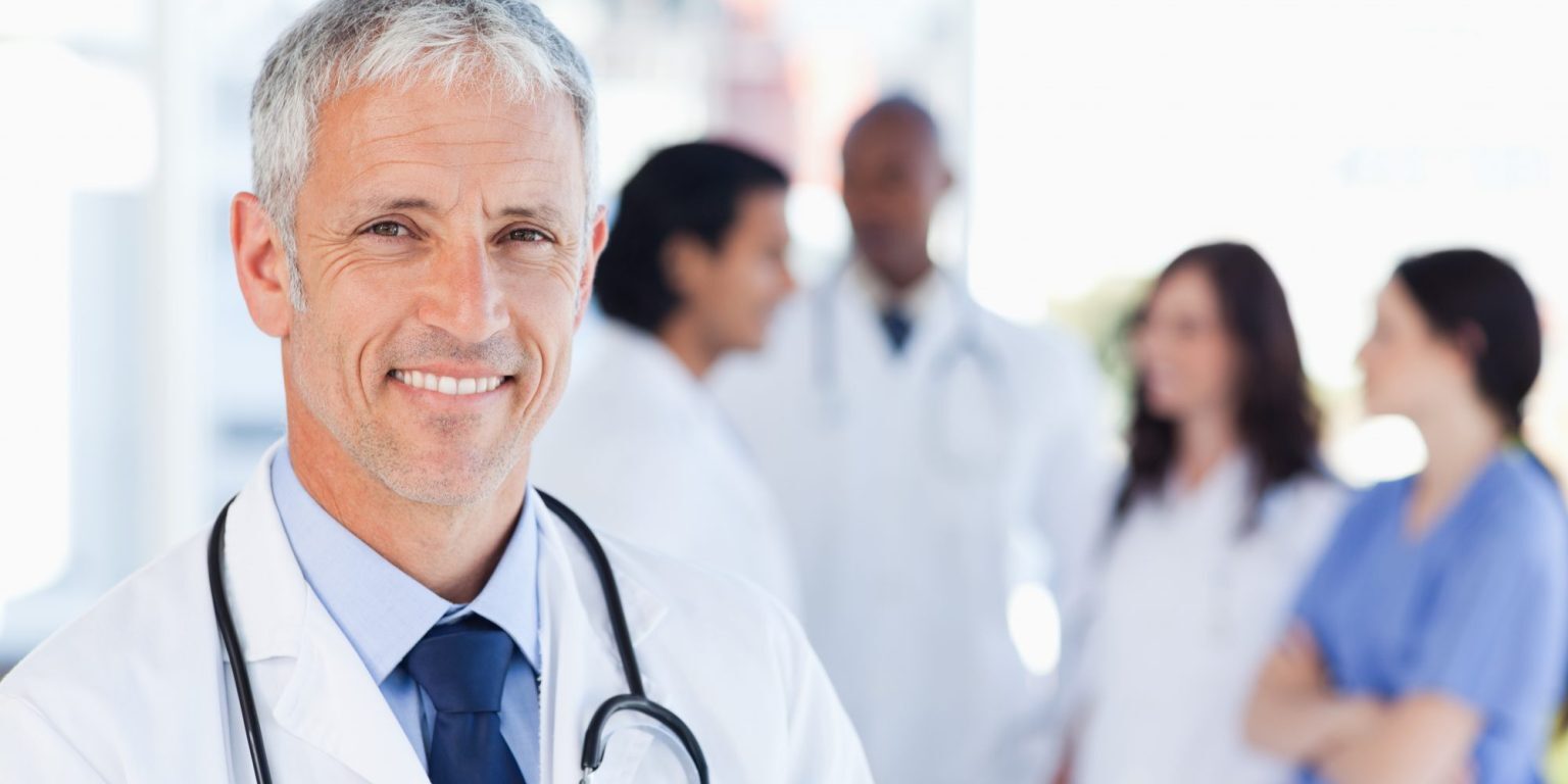 Smiling doctor waiting for his team while standing upright