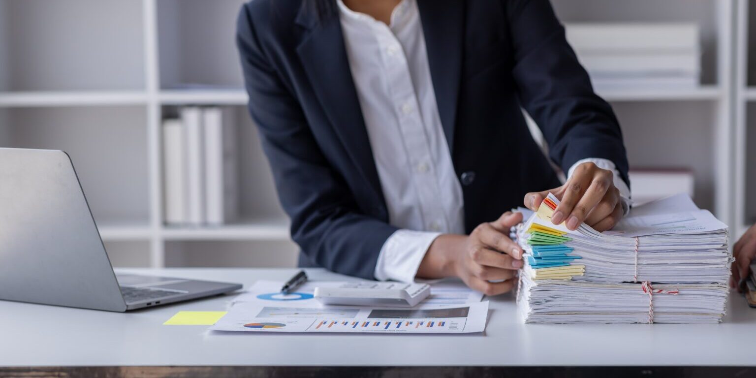 Business,Employee,Asian,Woman,Hand,Working,In,Stacks,Paper,Files